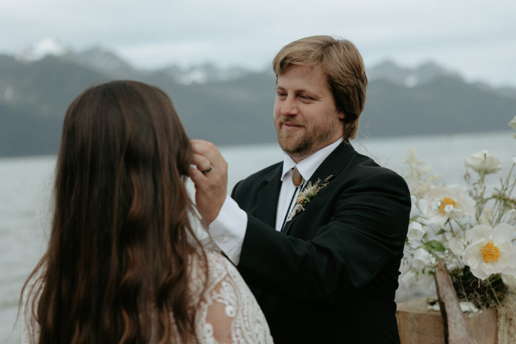 A man wearing a black suit moving a piece of hair out of a woman's face. 