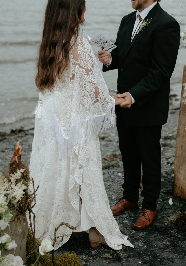 A couple holding hands during a ceremony on the beach. 