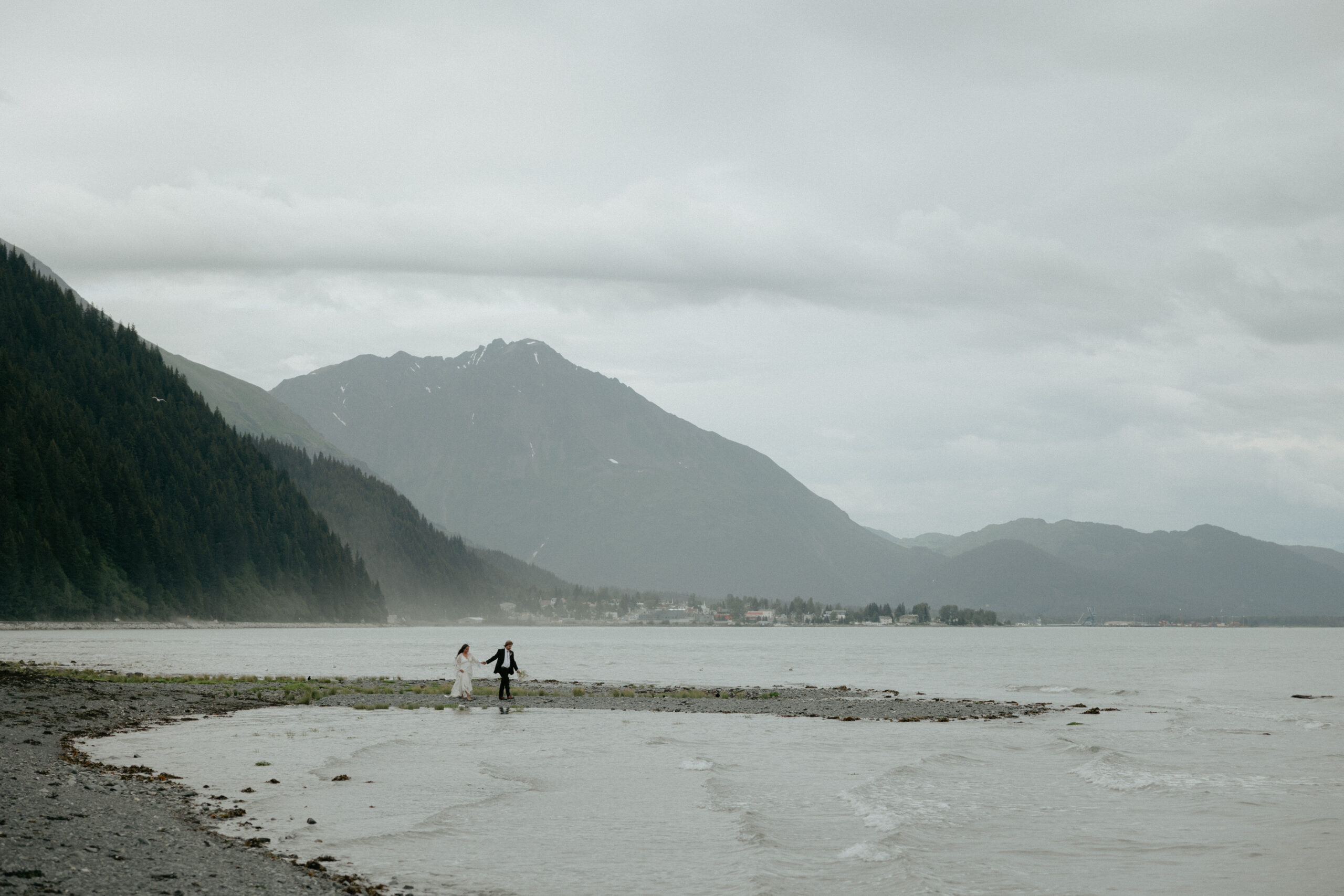 A couple walking along a beach in Seward, Alaska.