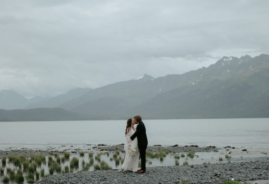 A couple kissing while standing on the beach. 