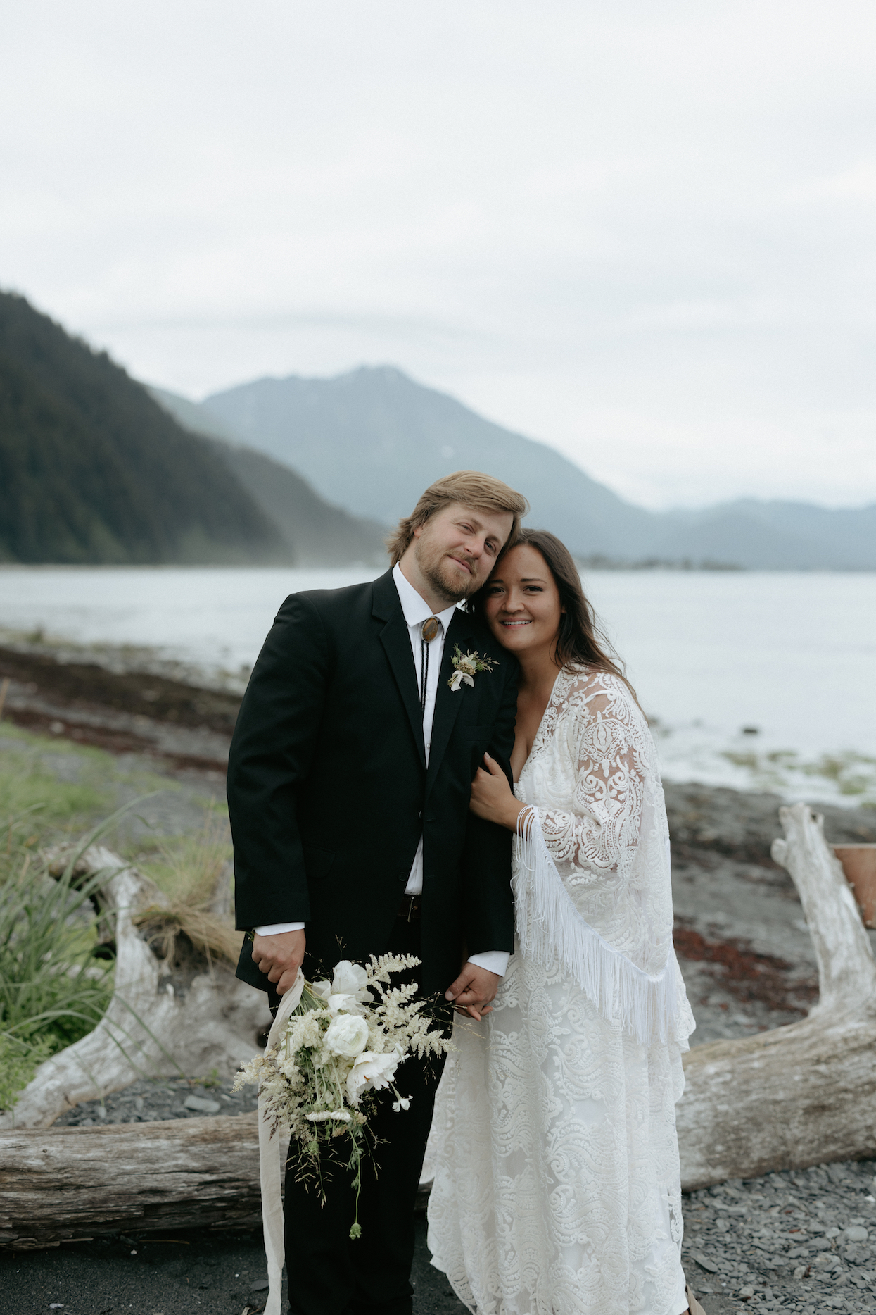 A couple snuggled together on the beach in Seward, Alaska. 