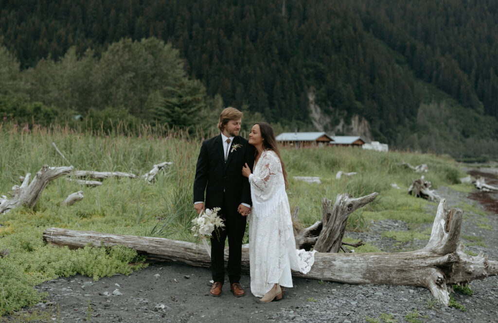 A woman holding onto a man's arm near a field of tall grass. 