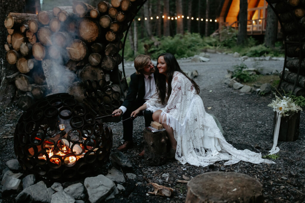 A couple in wedding attire roasting marshmellows. 