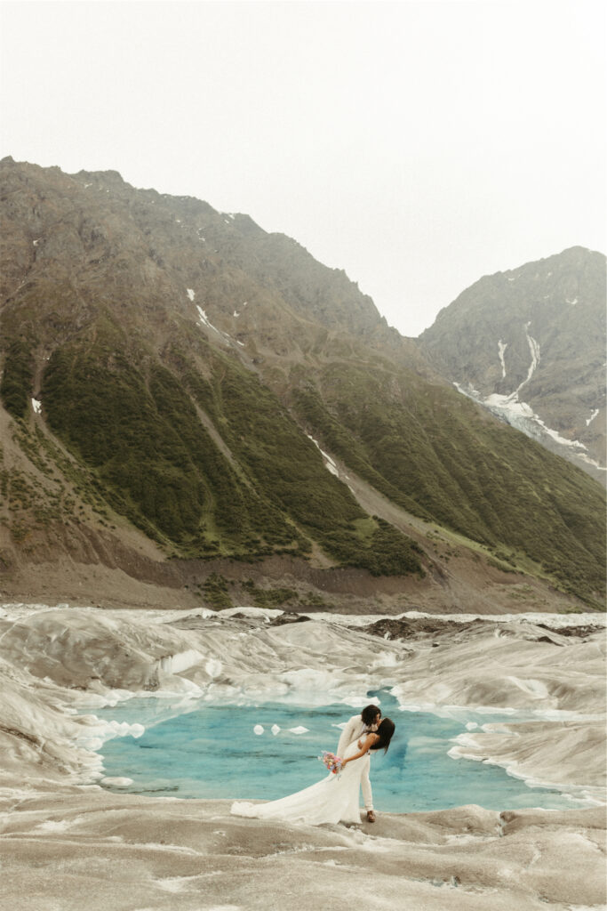 Couple kissing in front of a glacier pool after a helicopter tour in Alaska