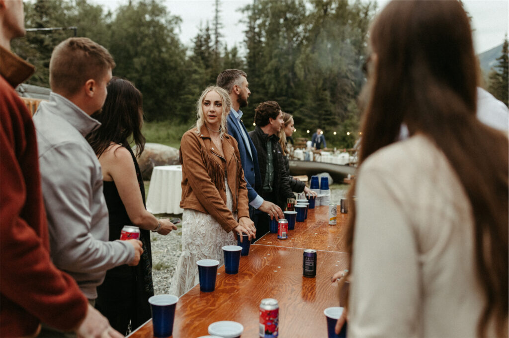 Friends of the bride and groom playing flip cup outside a wedding venue in Palmer Alaska
