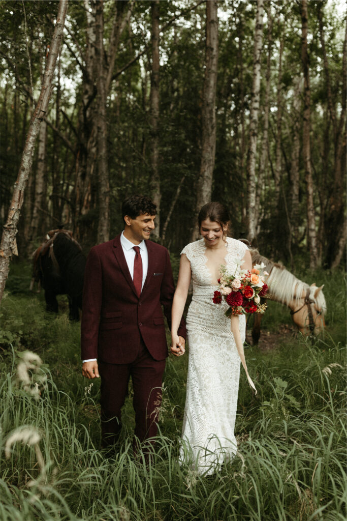 Couple walking in the woods in elopement with horses