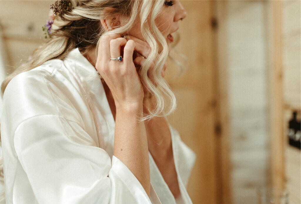 Woman putting in her earring while getting ready for her wedding