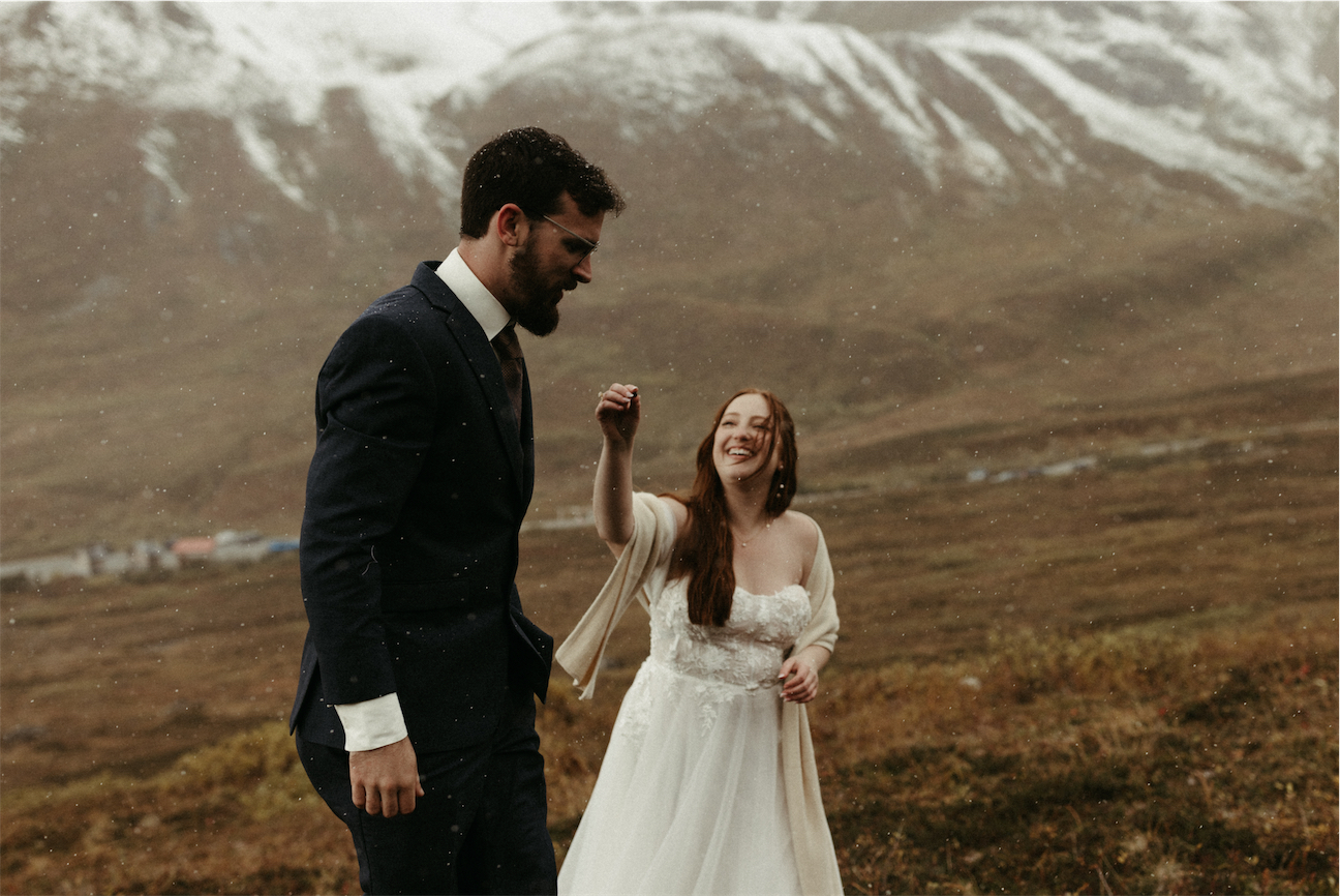 Bride and groom feeding one another blueberries on top of Hatchers pass during their fall elopement. 