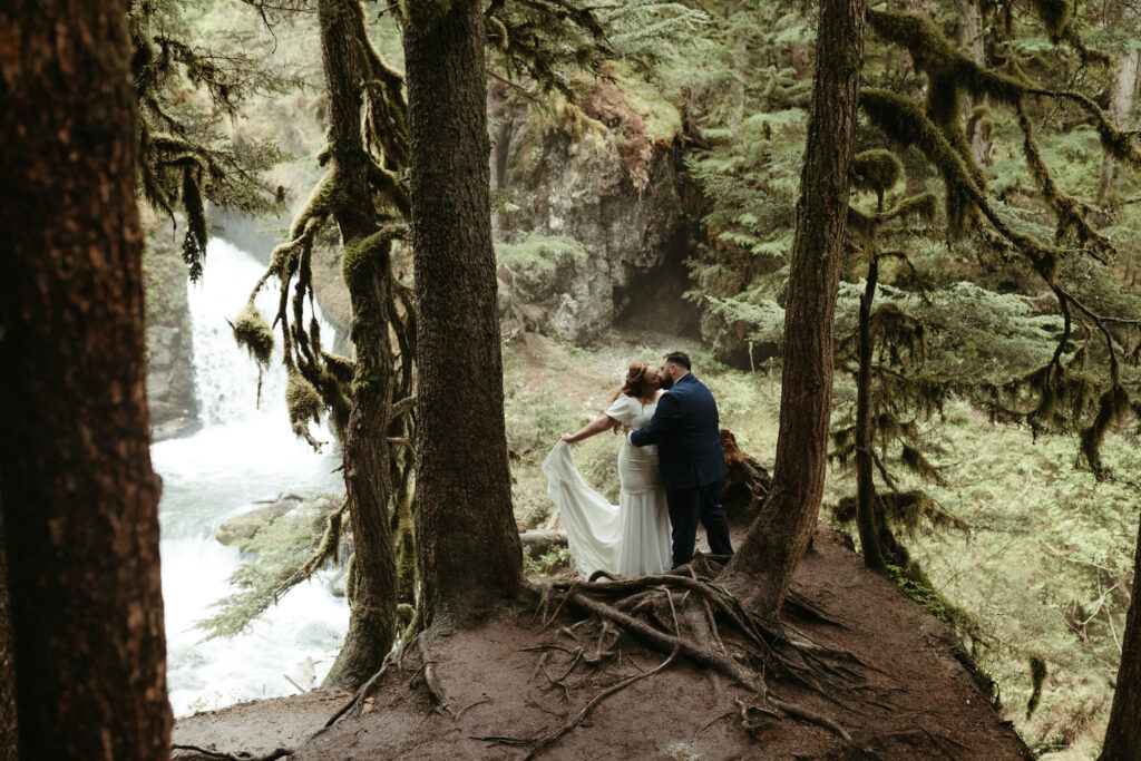 Couple standing among the forrest in Girdwood in wedding attire