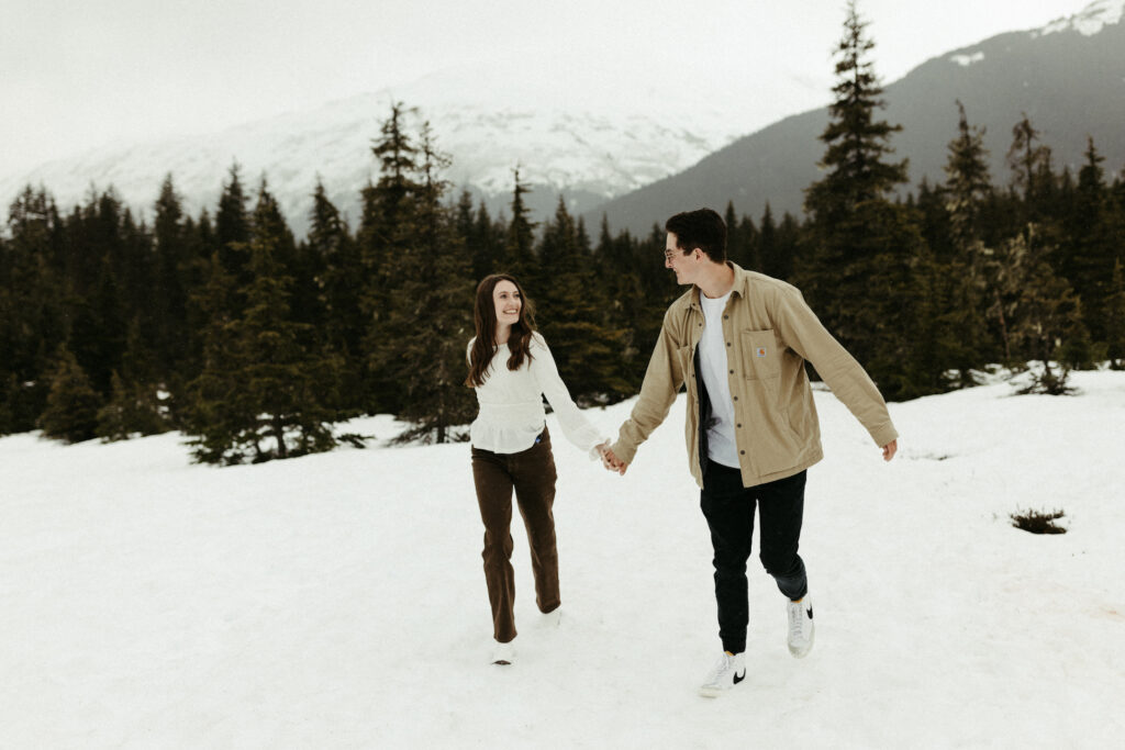 couple running in the snow during their engagement session in Alaska