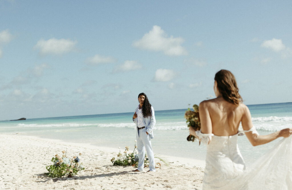 Woman walking towards man after their elopement ceremony on the beach.