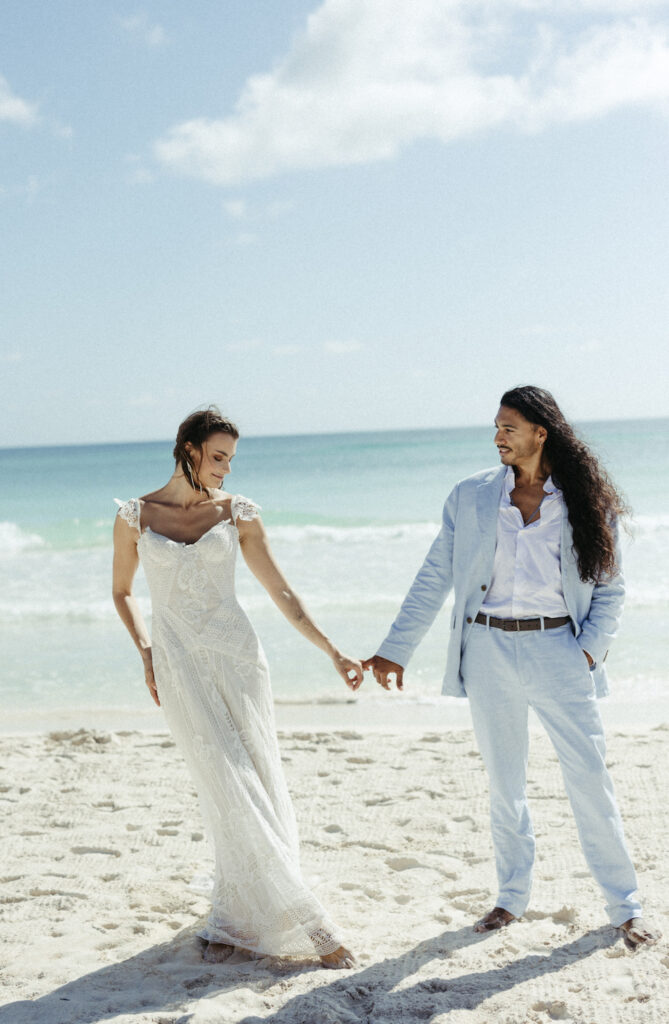 Couple holding hands and standing next to the ocean in Mexico
