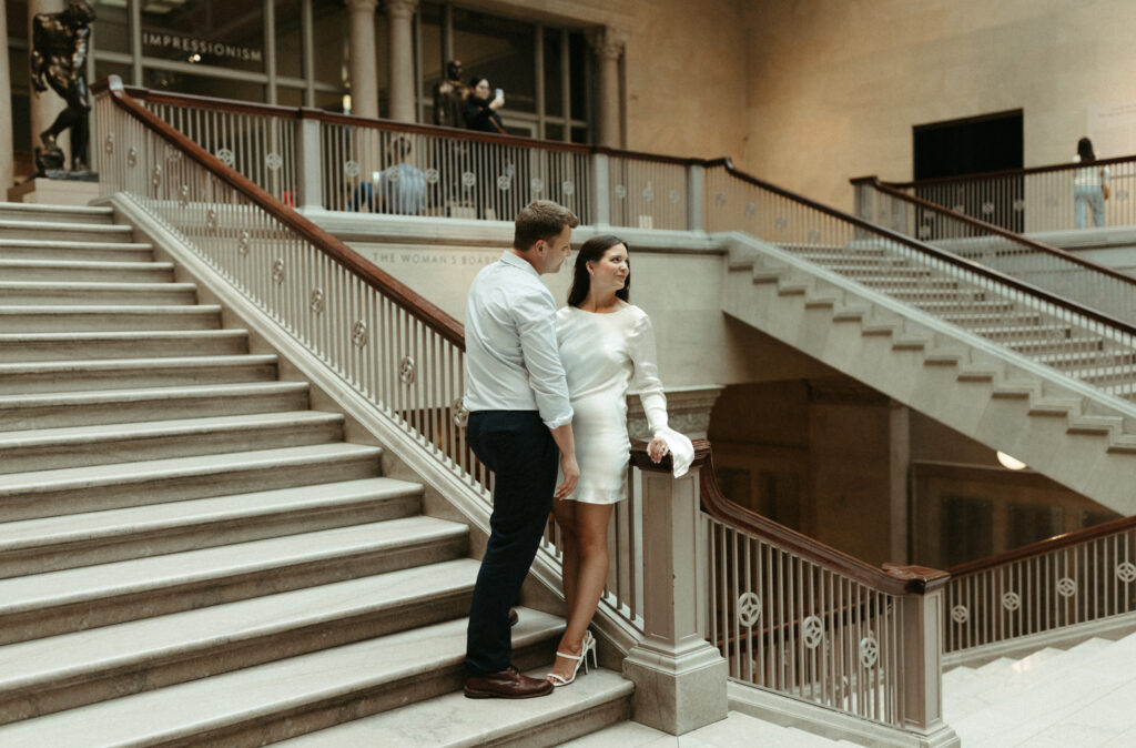 Couple standing close to one another while taking engagement photos in the art institute of Chicago.