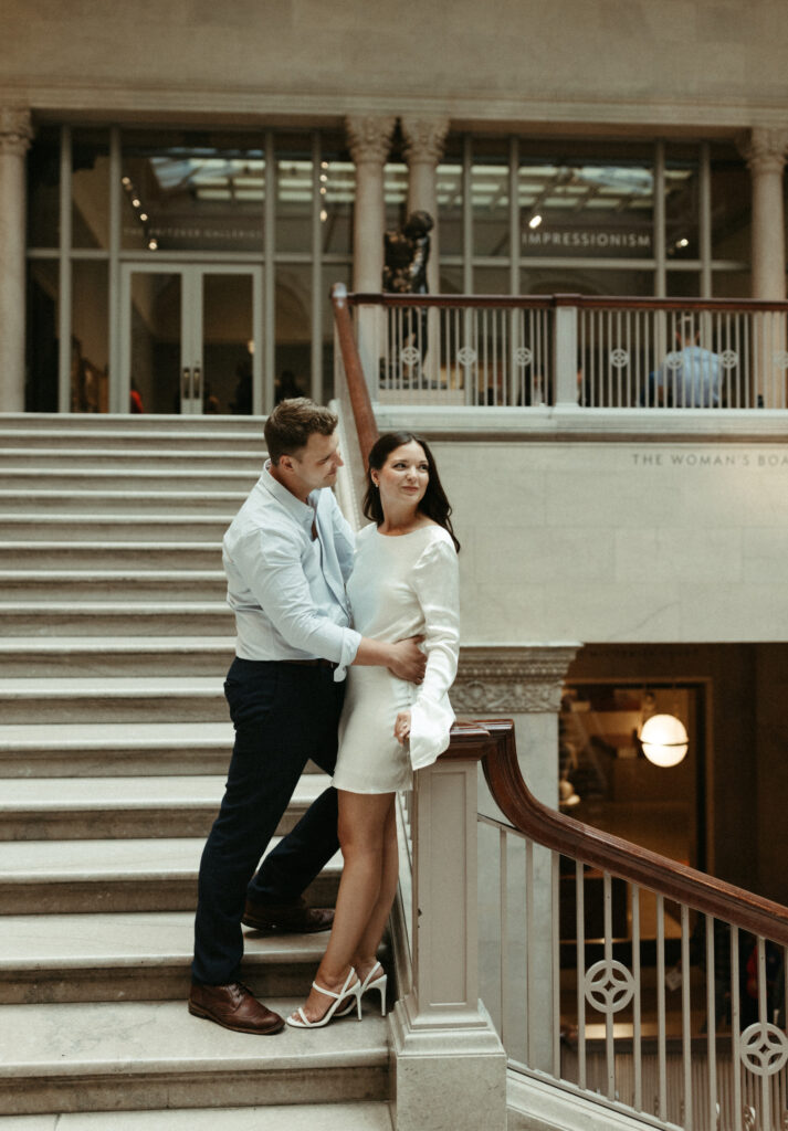 Couple snuggled close to one another during their engagement session the art institute of Chicago.
