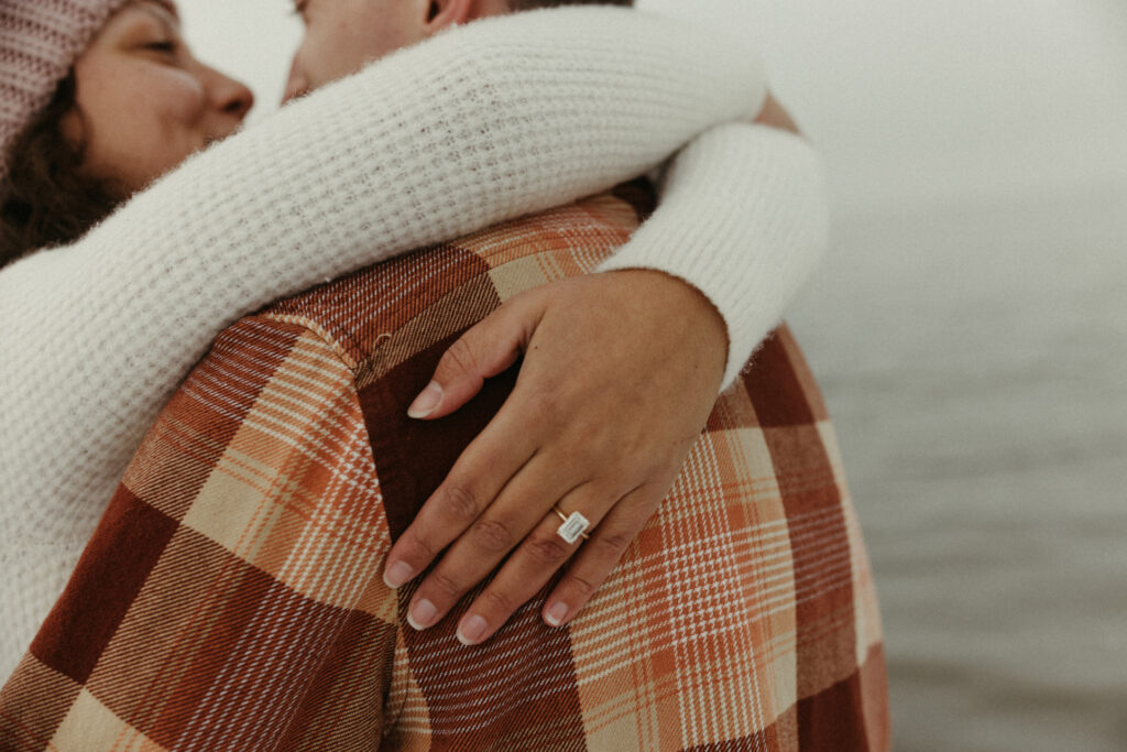 Woman holding man with her new engagement ring on her finger
