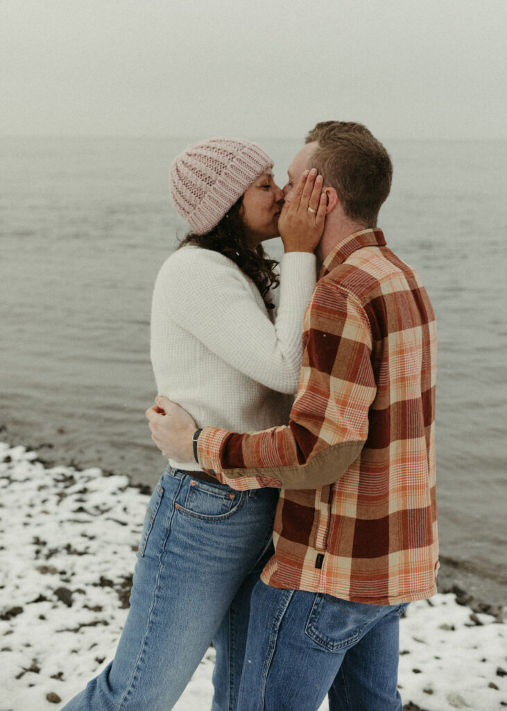 Woman holding onto mans face during a winter engagement session