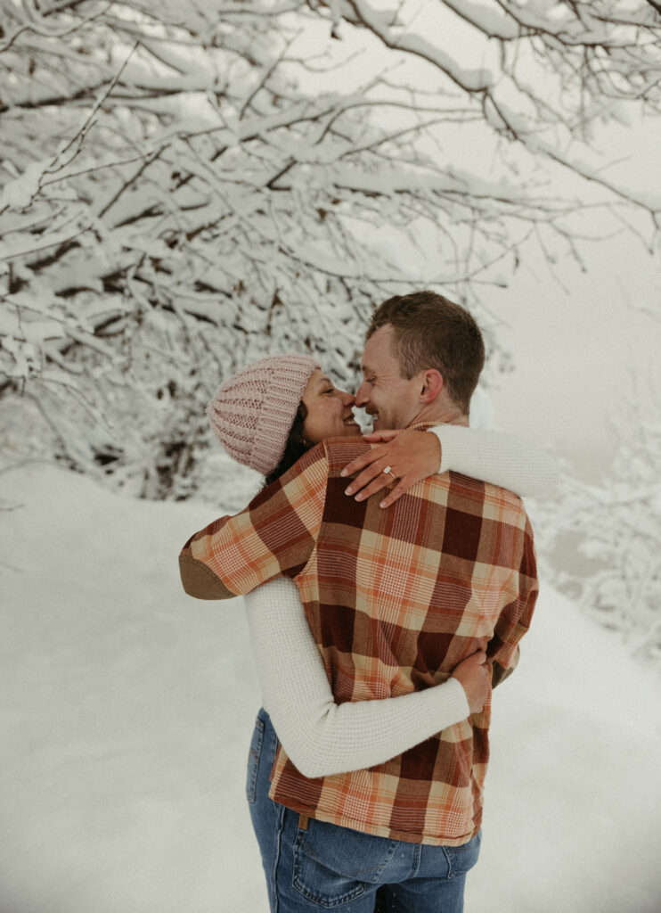 Couple holding onto one another after their outdoor proposal session in Anchorage Alaska