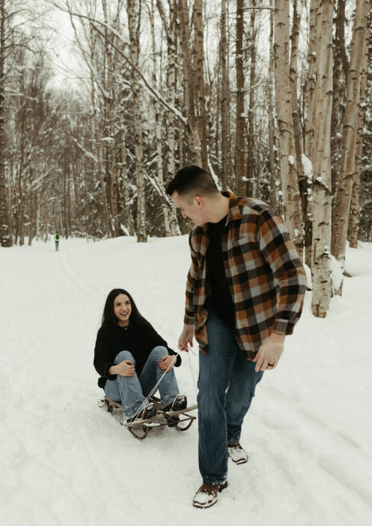 couple pulling one another on a sled