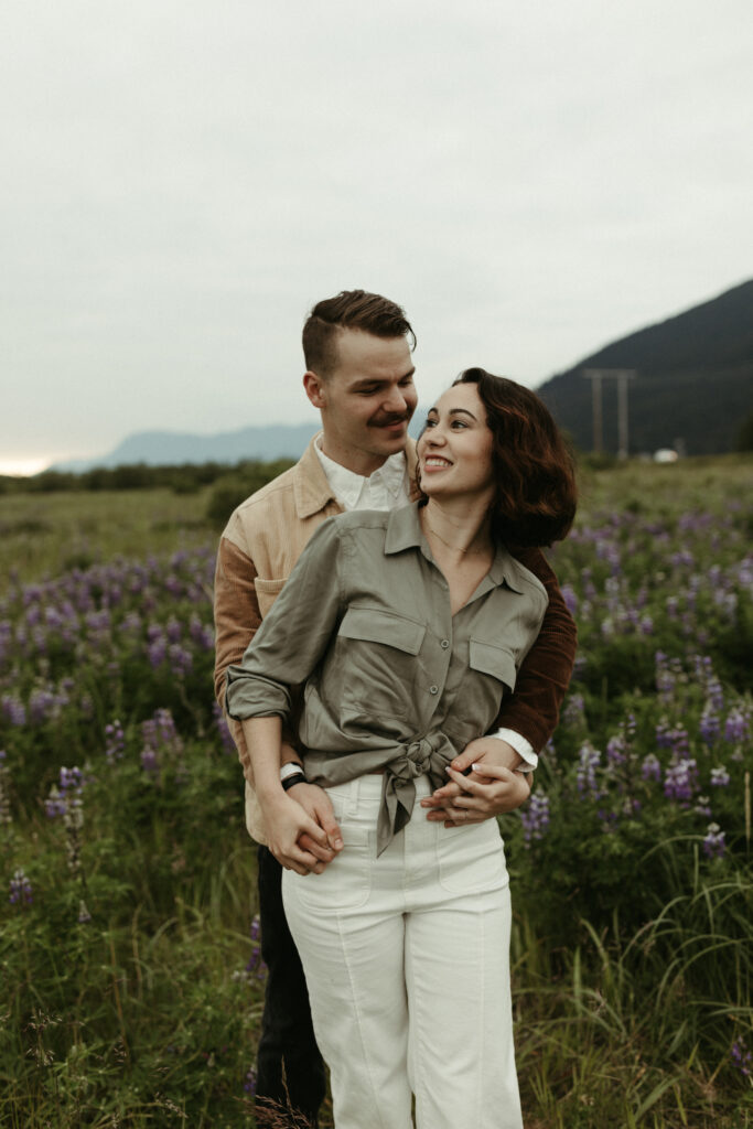 Man and woman smiling in a field of lupines in Girdwood, Alaska 