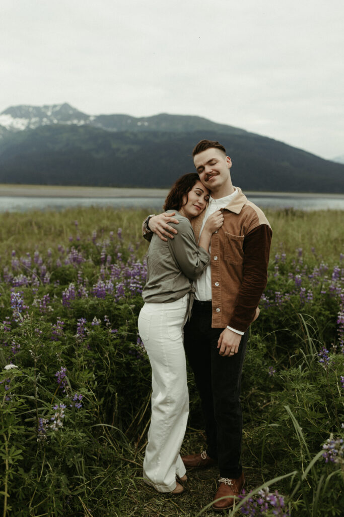 Couple holding onto one another while standing next to the mountains