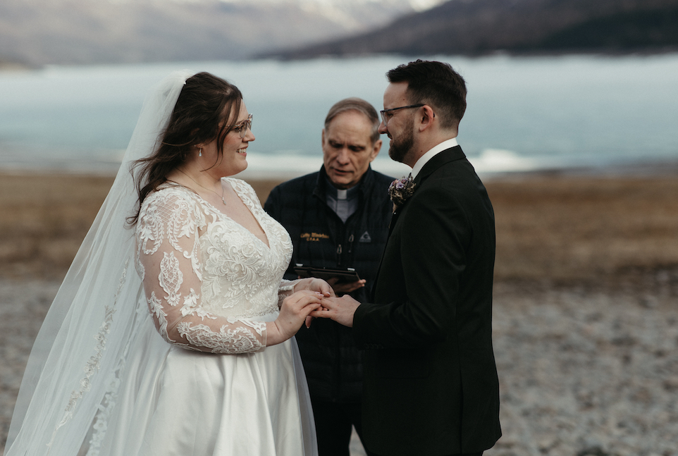 Woman putting ring on mans hand during an elopement ceremony. 