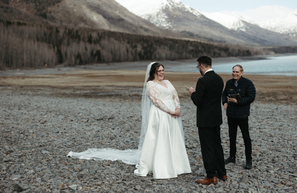 Couple reading vows aloud to one another during their elopement at Eklutna Lake. 