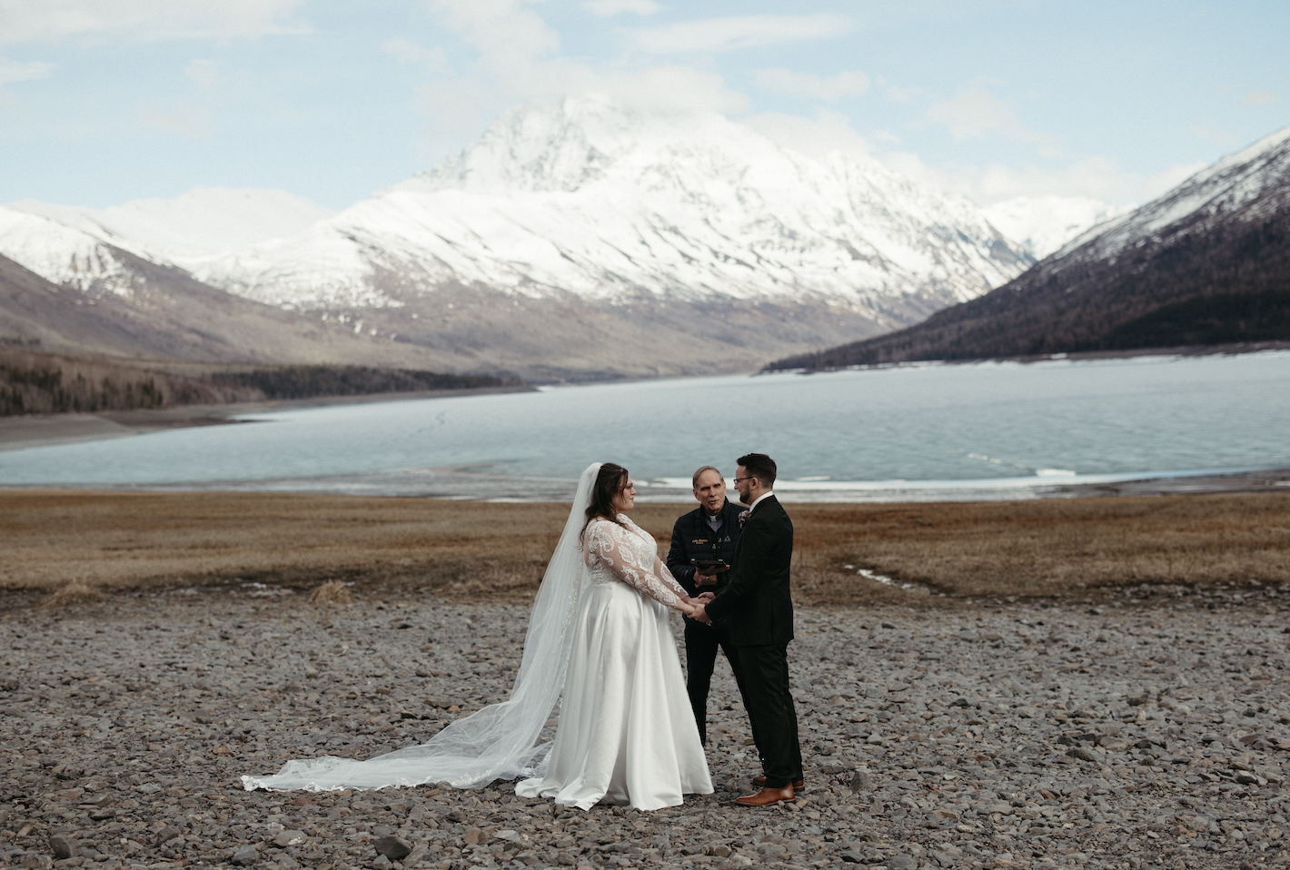 A couple holding hands for their wedding ceremony while eloping in Alaska during spring time. 
