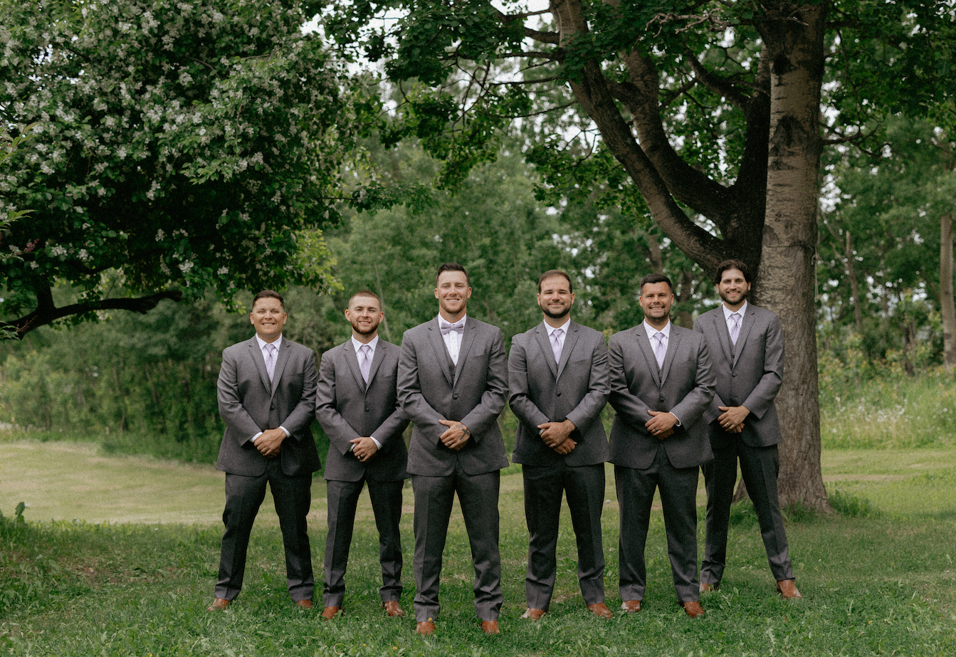 A group of groomsmen standing with their hands in front of them during a wedding in Alaska.