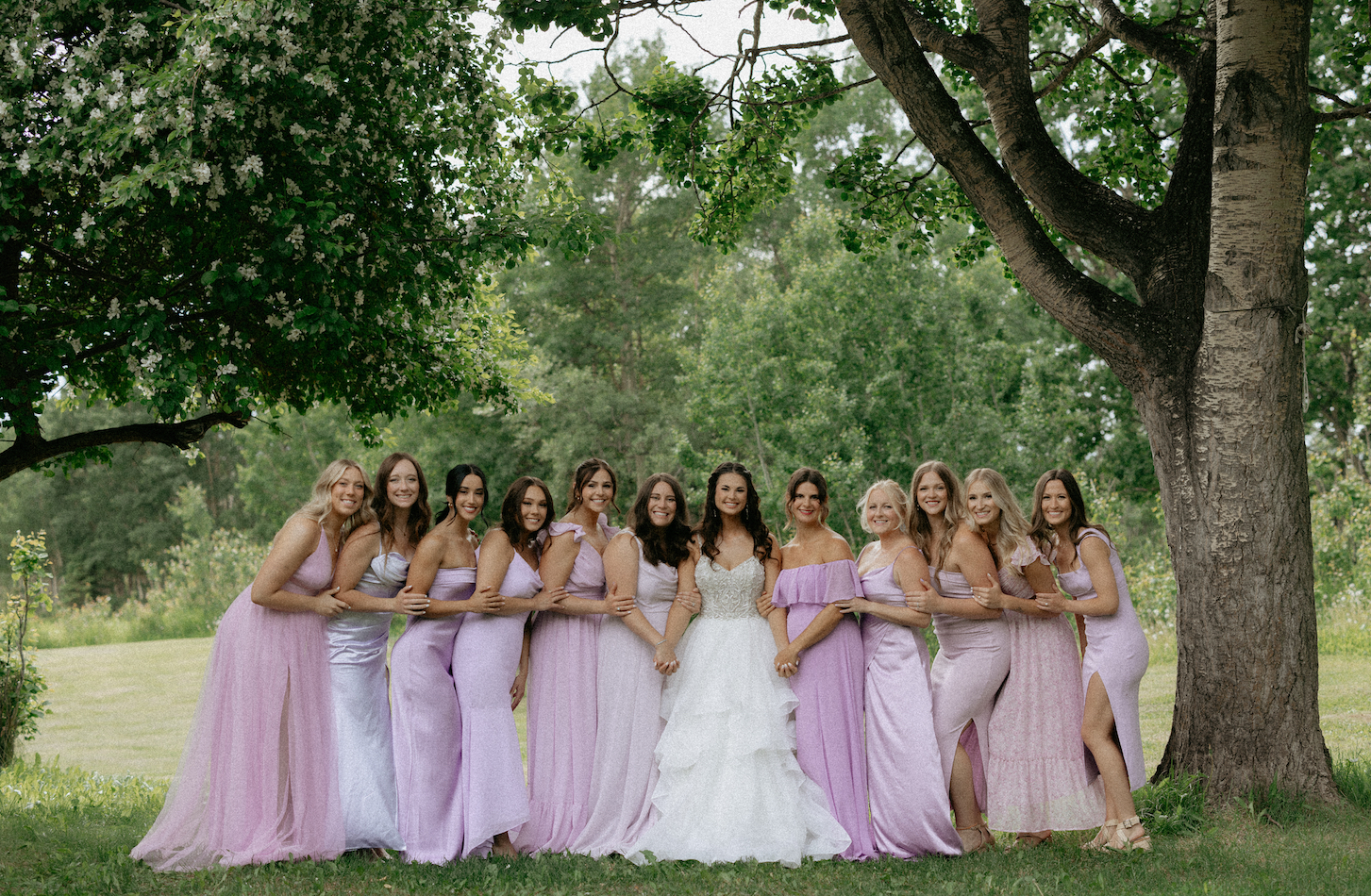 A woman with all of her bridesmaids standing under a tree. 