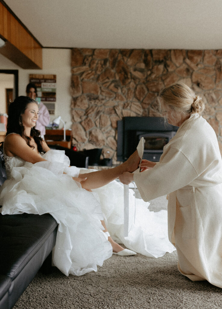 Mom helping her daughter put on her shoes for her Alaska wedding