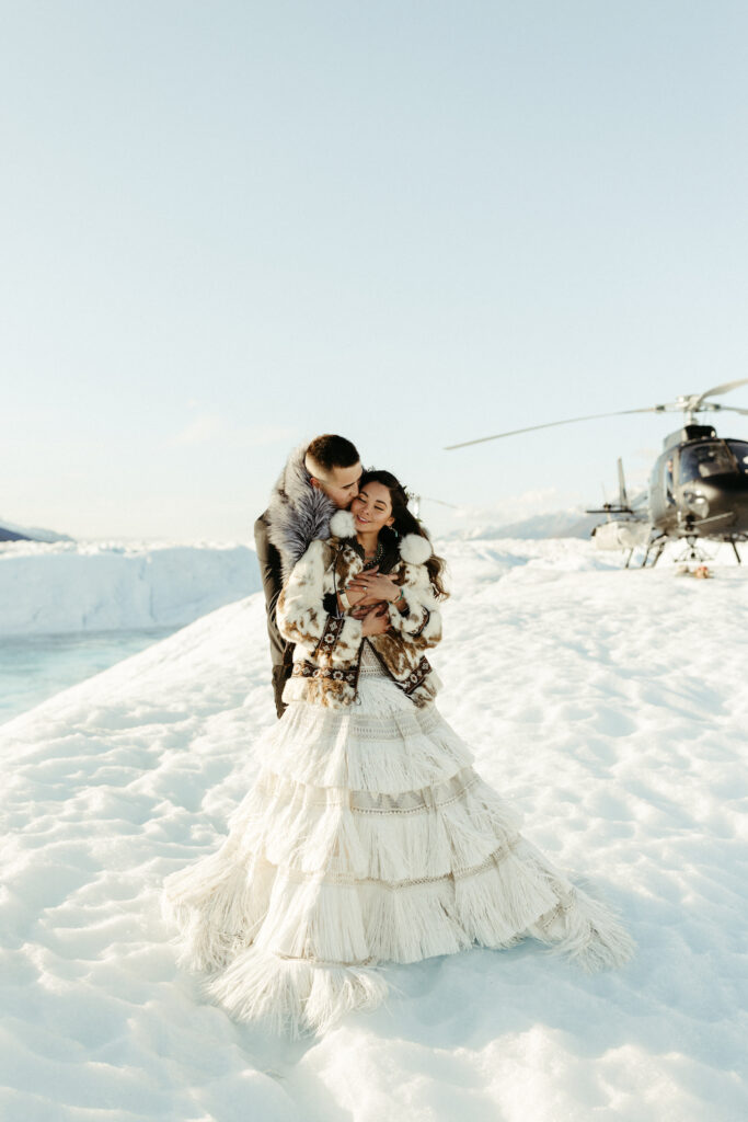 Couple snuggled close while on a glacier