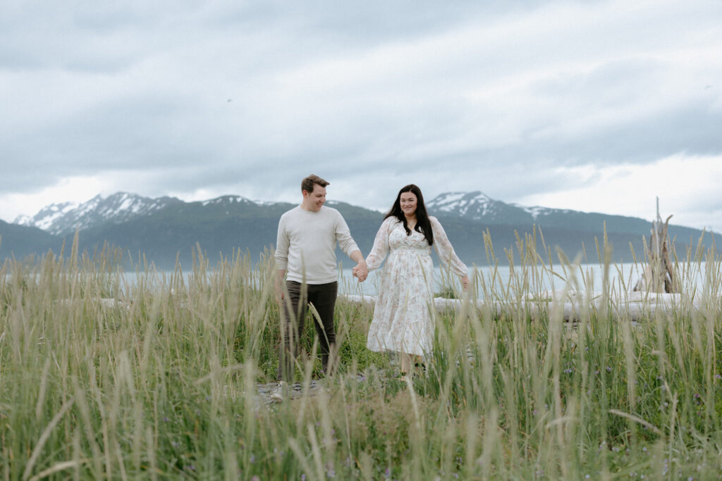 Couple walking through a field of grass while holding hands