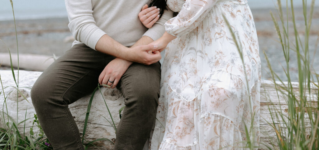 Couple holding onto one another while sitting on a log