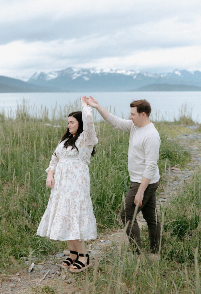 Man spinning a woman around while holding her hand. 