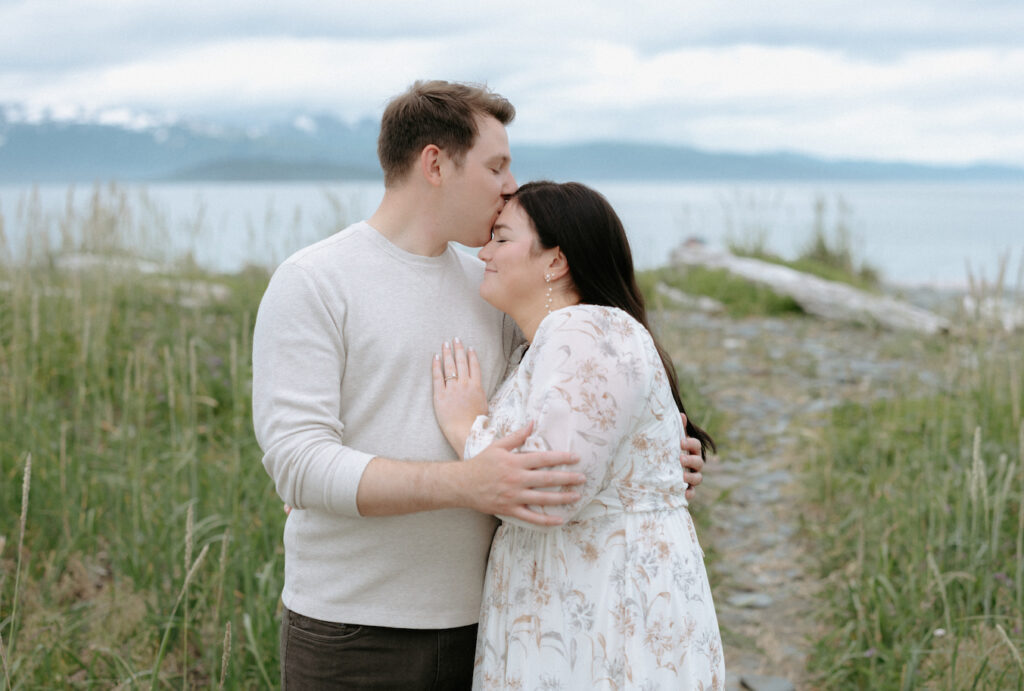 Man kissing woman's forehead while she has her hand on his chest.