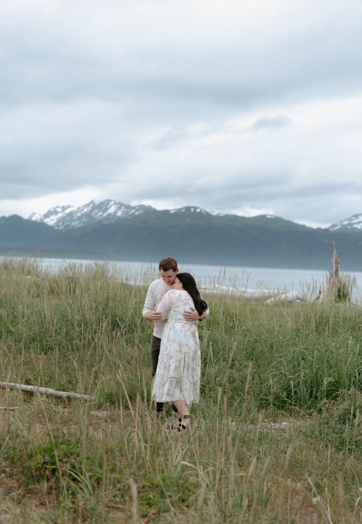 Man embracing a woman while standing in a field of grass