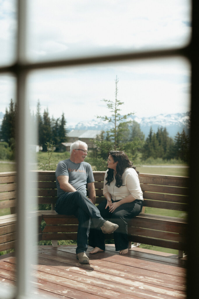 Bride and her father sitting on the deck at a wedding venue in Homer, Alaska.