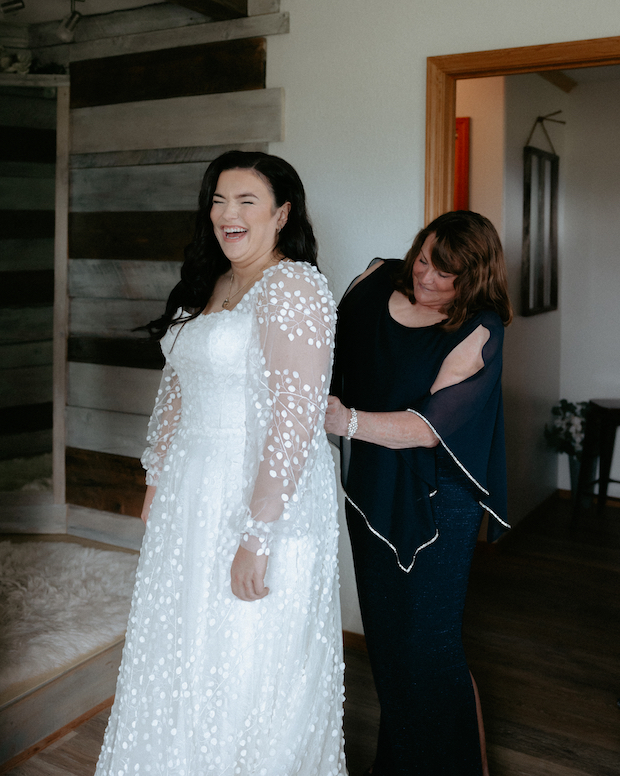 Mother of the bride helping her daughter get into her wedding dress. 