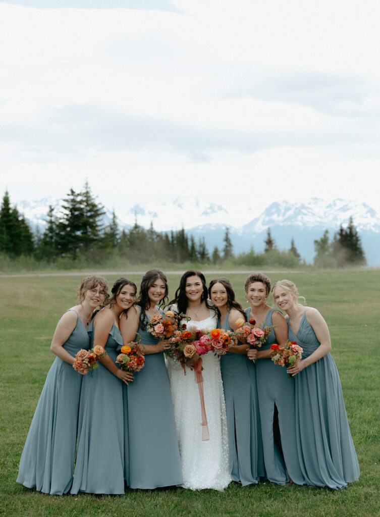 Woman surrounded by other women while holding flowers.