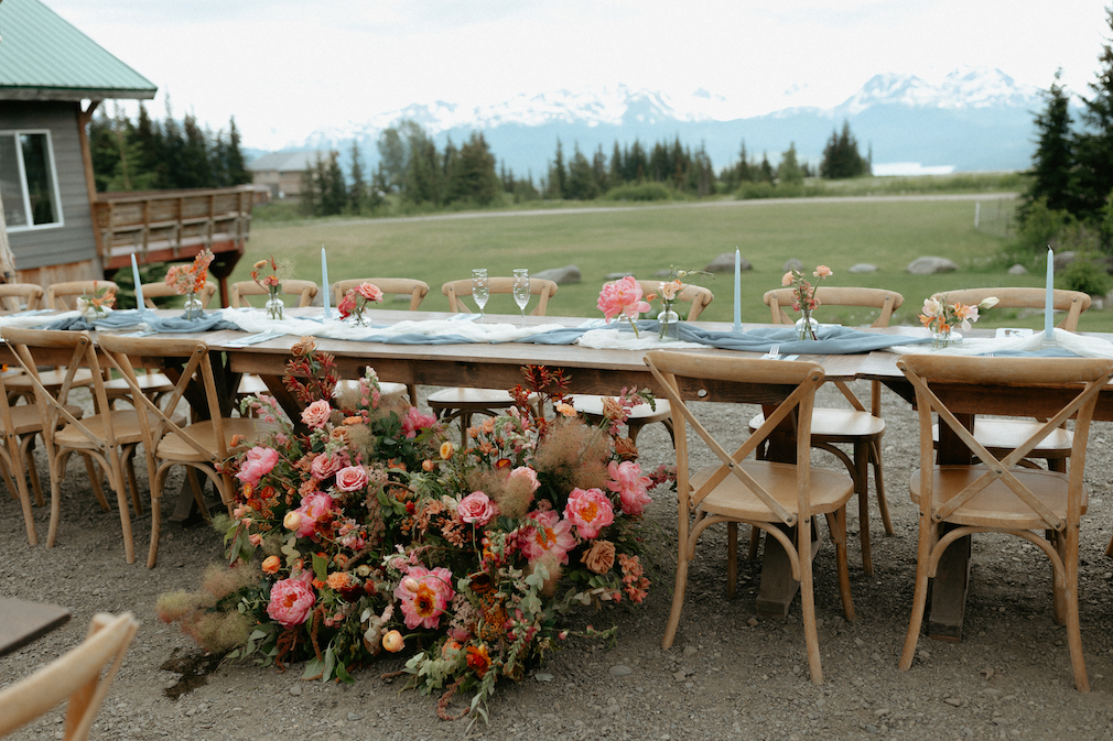 Florals sitting on the ground in front of a wooden table. 