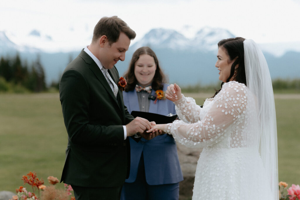 Man putting a ring on a woman's finger. 