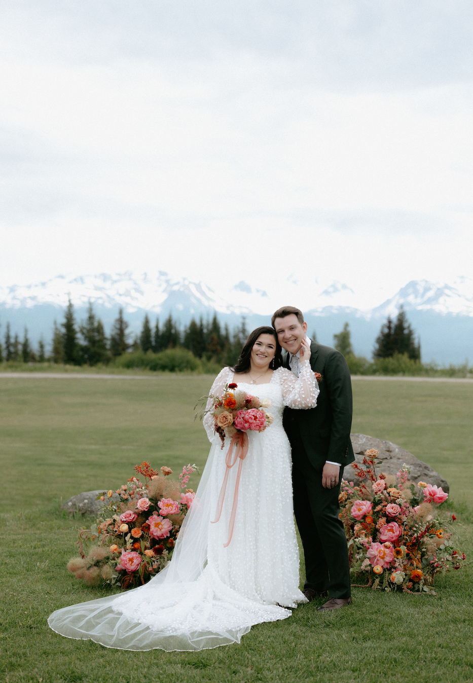 A couple standing in front of their wedding ceremony florals.