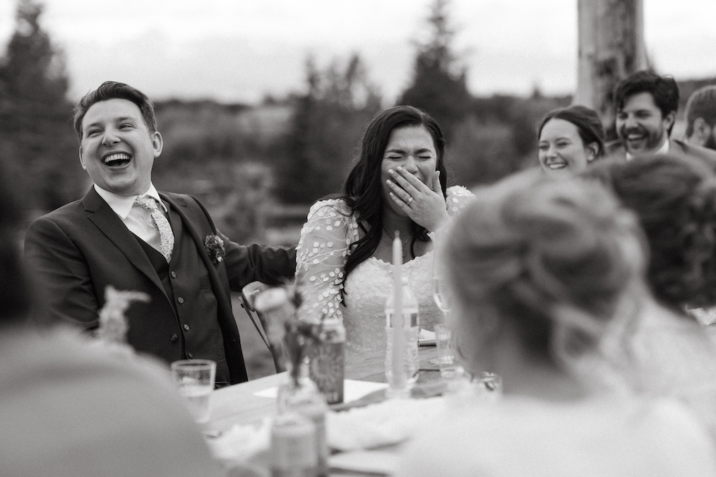 Couple laughing and smiling together at their reception. 