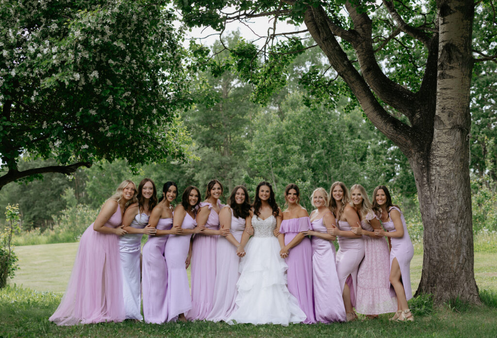 Group of woman wearing dresses and hugging on another while standing under a tree in Wasilla, Alaska. 