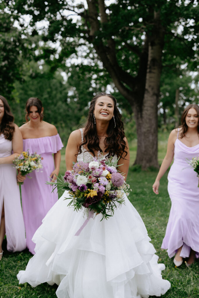 Woman walking while holding a purple flower bouquet. 