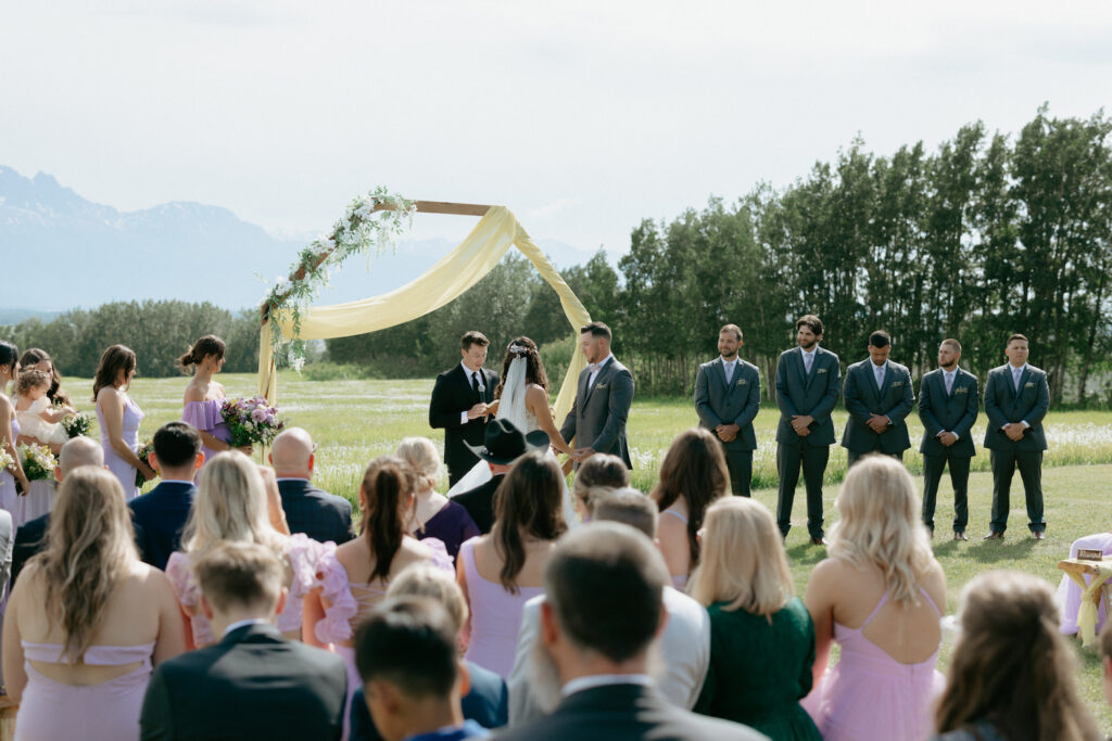 Couple surrounded by family and friends during an Alaska wedding ceremony. 