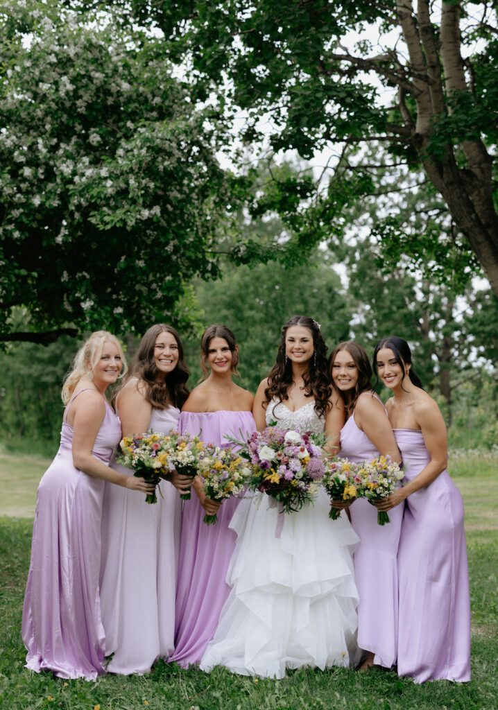 Group of woman standing next to one another while holding flowers during a wedding in Alaska