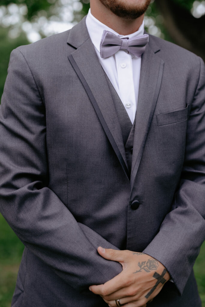 Man wearing a grey suit and a purple bowtie.