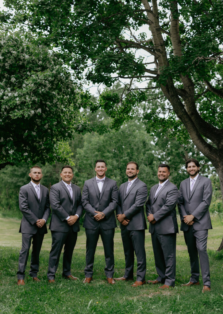 A group of men standing together wearing suits for wedding group photos in Alaska.