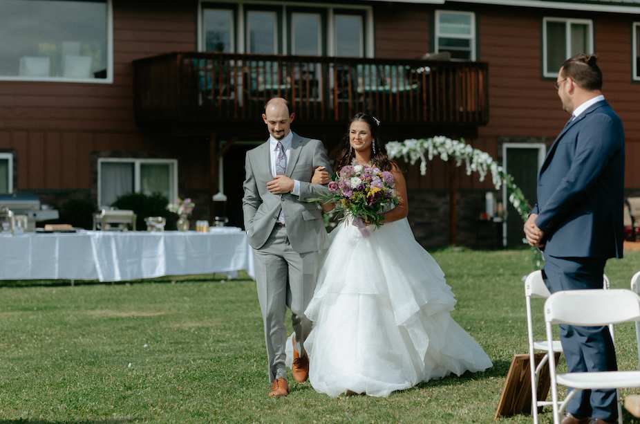 Man walking his daughter down the aisle during a wedding ceremony in Alaska.